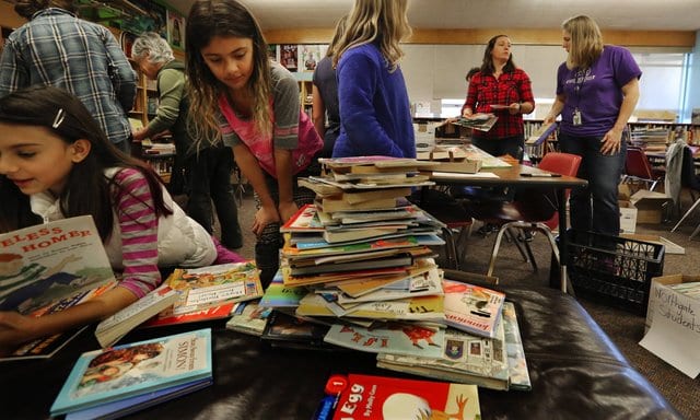 Books in a pile with students looking at them