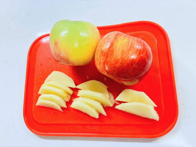 Five Senses Activities an image of two apples and apple slides on a red cutting board