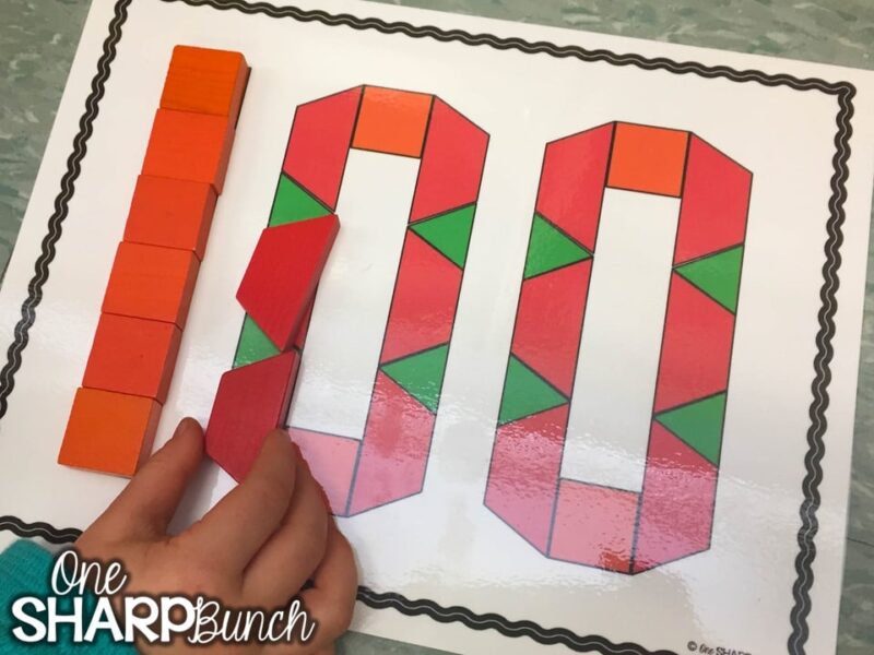 A student fills in the shape of the number 100 with pattern blocks