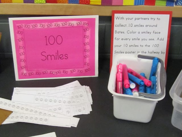 bright pink piece of paper with 100 smiles printed on it next to a tub with colored markers