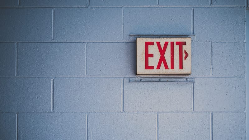 Exit sign in school building to symbolize educators leaving the profession and jobs for former teachers