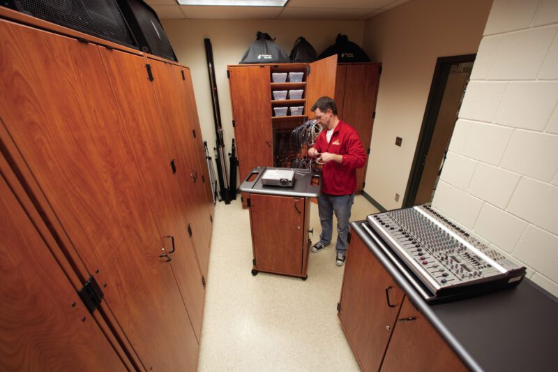 Teacher standing in storage room filled with Fixed Media Storage cabinets