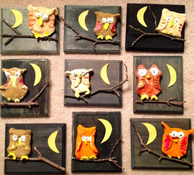 Brown and orange clay owls perched on sticks and mounted on black plaques (First Grade Art)