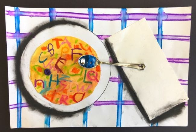Mixed media art project showing bowl of alphabet soup with a napkin and a real spoon holding an alphabet bead