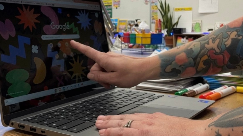 A teacher's finger pointing to her Google Chromebook screen