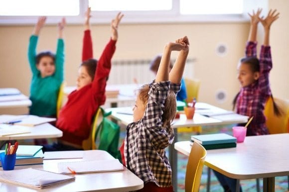 Students stretching their arms in classroom