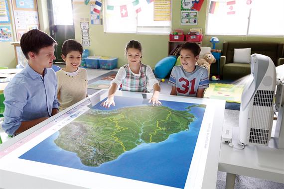Kids around table with interactive projector in a classroom