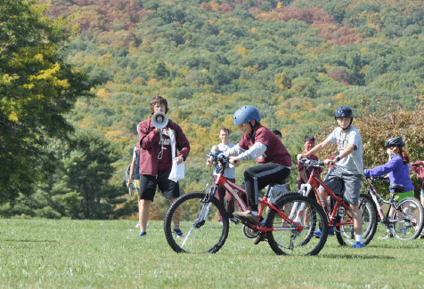 Kids with helmets on riding across a field