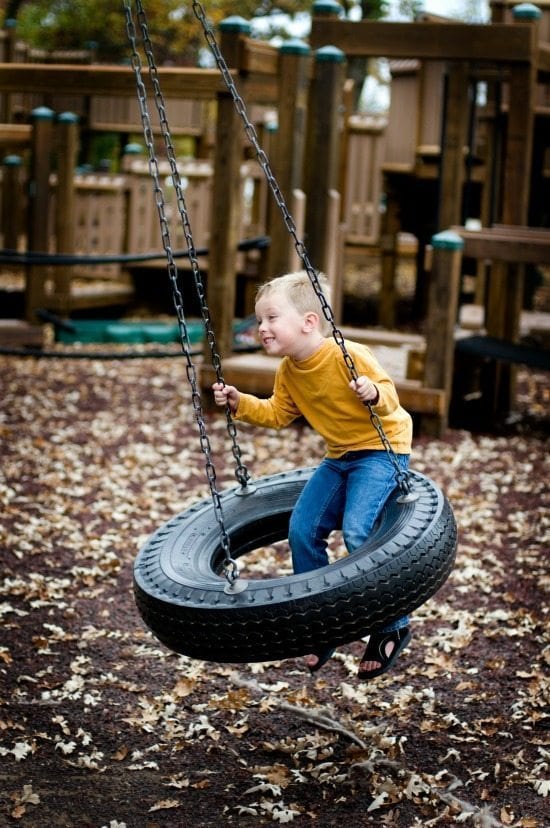 Boy on tire swing on playground.