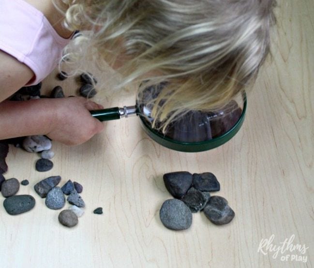 Small child looking at rocks through a magnifying glass