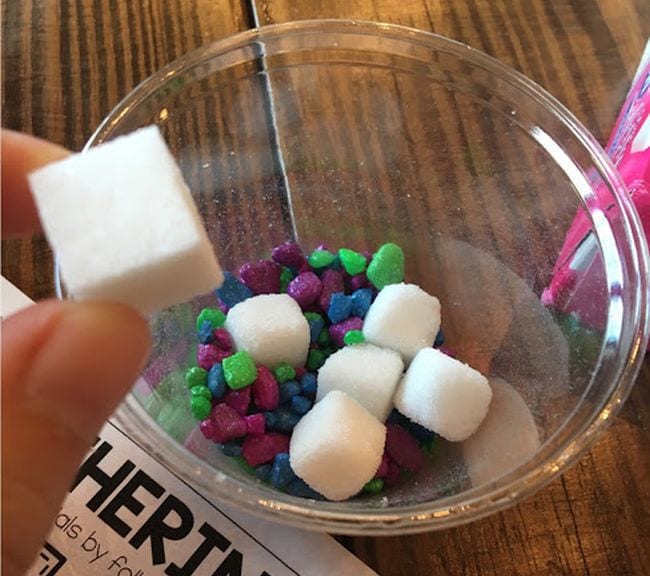 Plastic cup full of colorful pebbles and sugar cubes