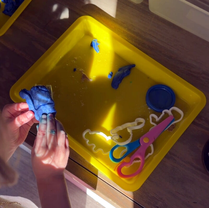 Child using 3D printed cookie cutters to make dinosaur shapes on a yellow tray