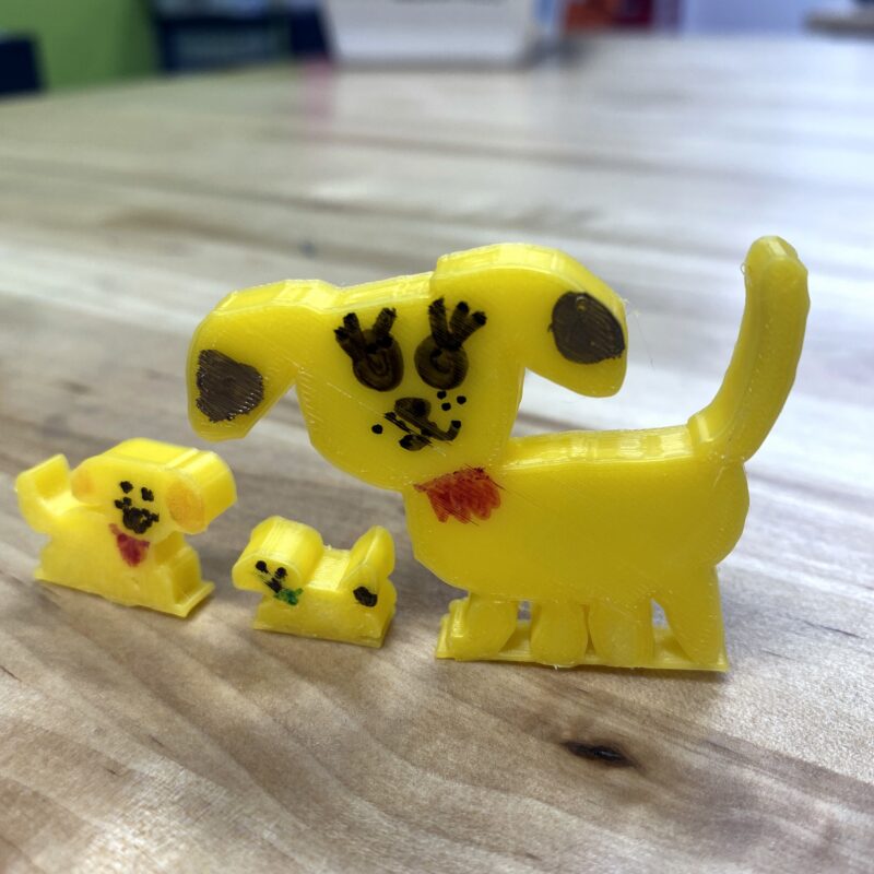 3D printed yellow dog and two smaller dogs standing on a desk