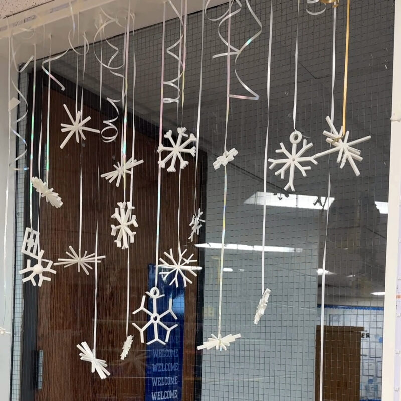 3D printing snowflakes hanging from strings in a classroom window