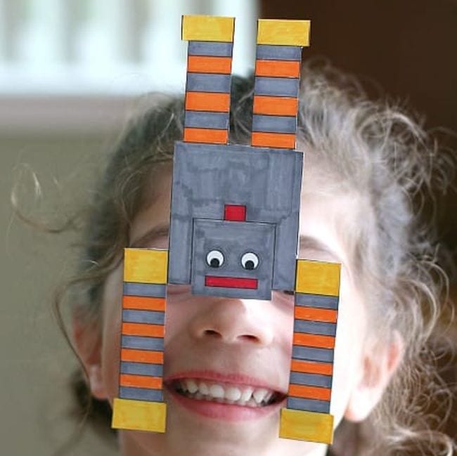 Child balancing a paper robot on their nose
