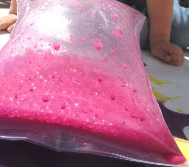 Sealed plastic bag filled with pink paint, swelling with air