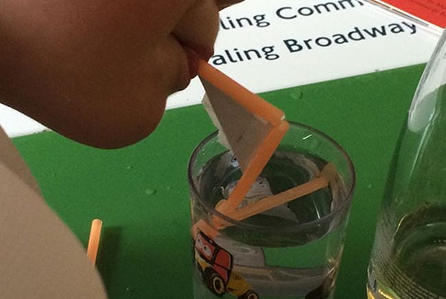 Science student blowing through a crooked straw into a glass of water