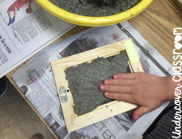 Third grade science student pressing paper pulp into a wood photo frame