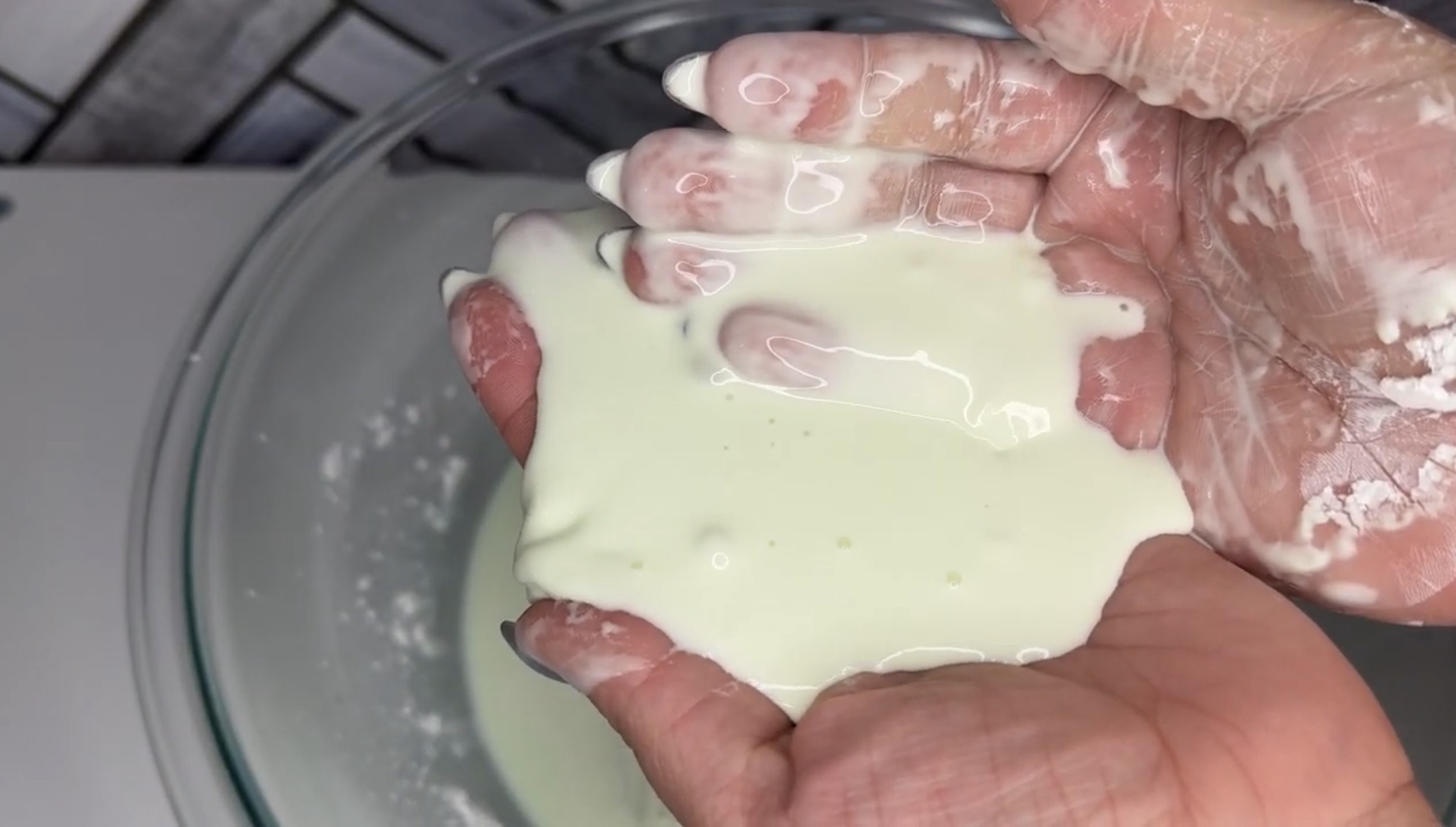 Hands holding oobleck over a plate.