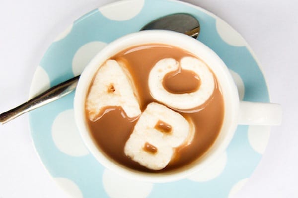 Alphabet marshmallow letters float in a cup of hot cocoa as an example of alphabet activities