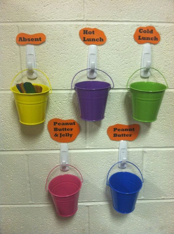 Multicolored buckets hanging on wall on white hooks with lunch options