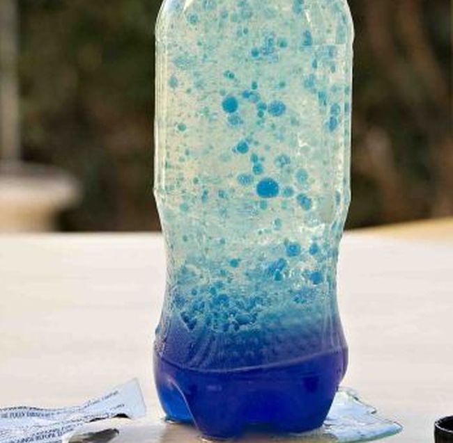 Soda bottle filled with blue liquid floating in globules (Fifth Grade Science)