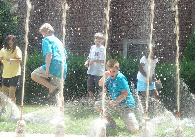 Students looking surprised and running away as foam geysers explode from soda bottles (Fifth Grade Science)