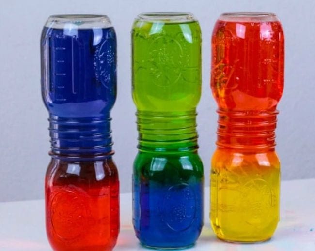 Mason jars stacked with their mouths together, with one color of water on the bottom and another color on top