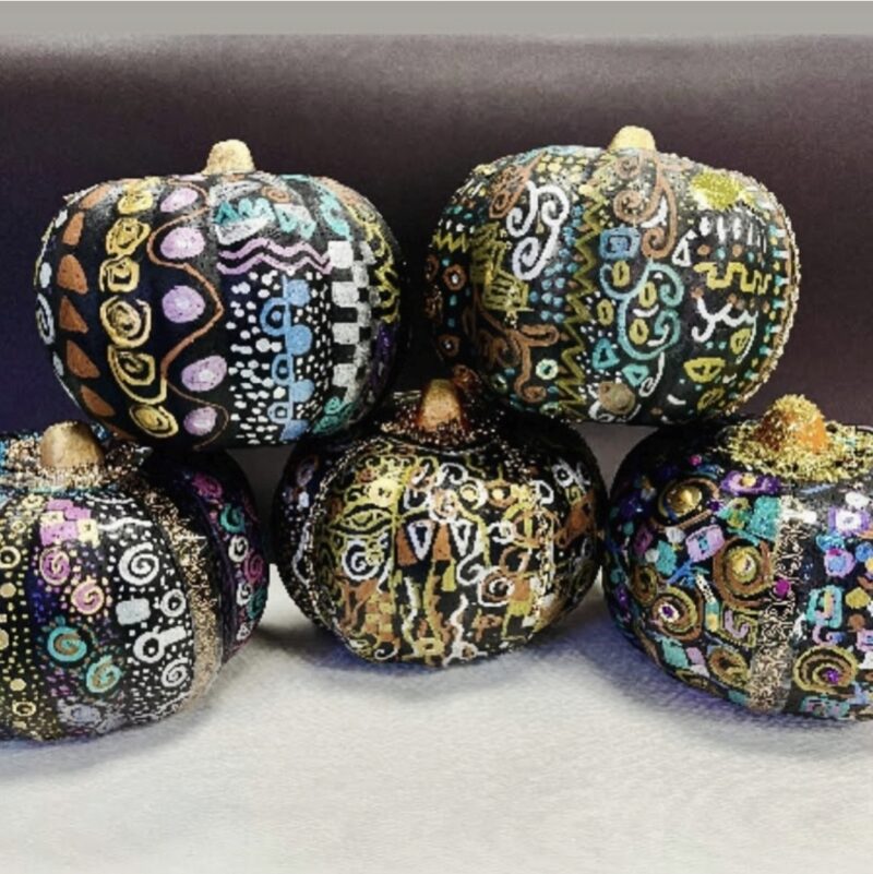 Pumpkins painted black and covered in designs using metallic markers