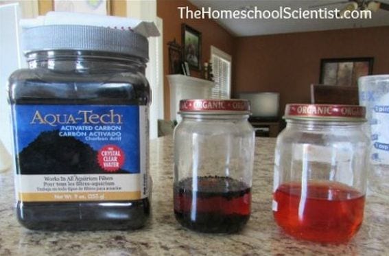 Bottle of powdered activated charcoal next to two jars of colored water 