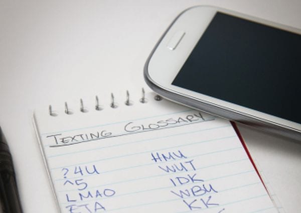 Cell phone and notebook with list of texting terms
