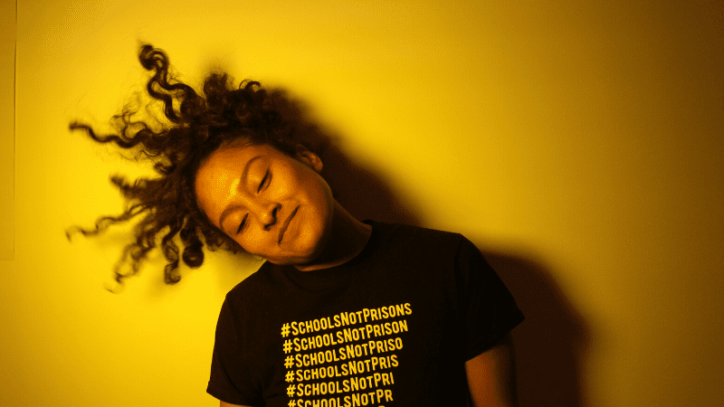 Teen wearing a shirt that says #schoolsnotprisons - high school photography lessons
