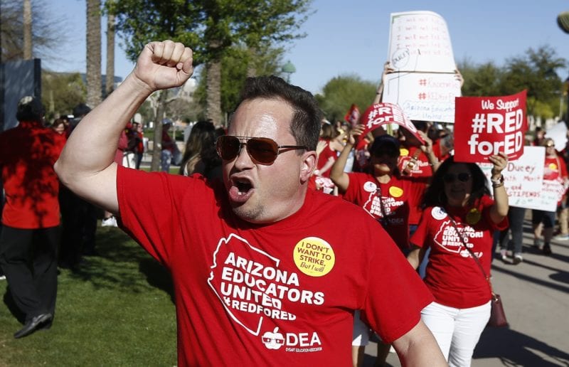 Teacher raising his fist in protest- teachers poverty