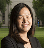 An Asian American woman with shoulder length hair is seen smiling at the camera.