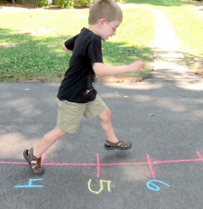 Young student running along a number line drawn on the sidewalk