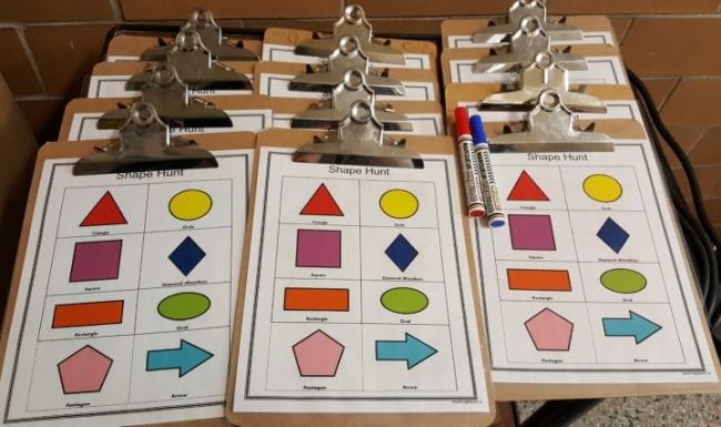 Clipboards with Shape Hunt worksheets showing colorful pictures of circles, triangles, and more (Active Math Games)