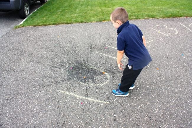 Young student splashing a water balloon onto the number ten drawn on the sidewalk (Active Math Games)