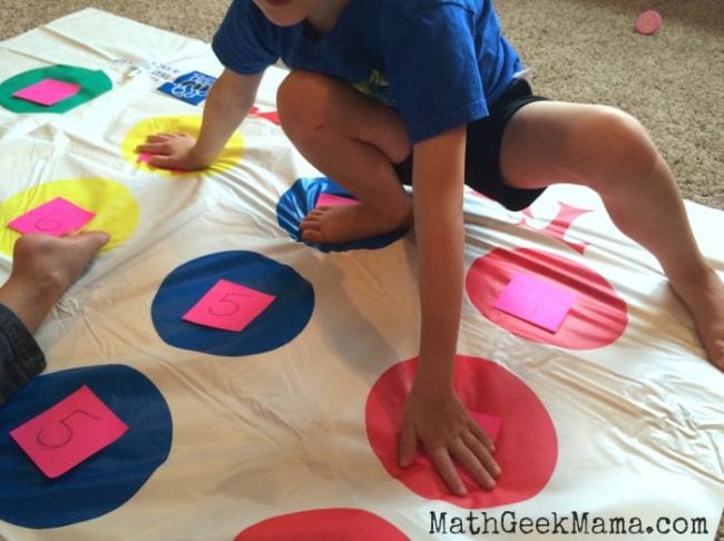 Students playing Twister with sticky note numbers on each circle