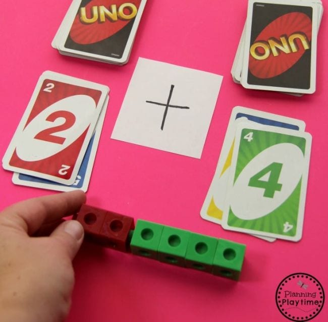 Child using UNO cards and math cubes to represent addition facts