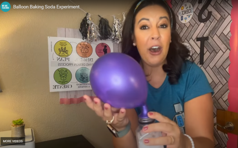 A woman with a shocked expression is seen holding an inflated purple balloon that is attached to a clear container.