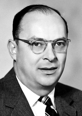 A middle aged man with glasses is seen from a 3/4 view in a black and white photo.