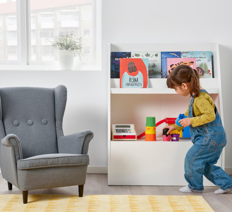 A child is seen standing in front of a bookshelf