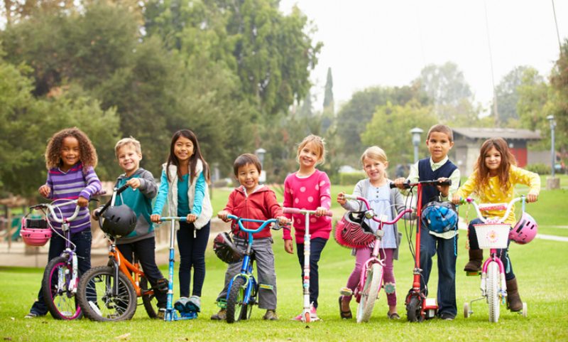 school children lined up in a row on their bikes and scooters