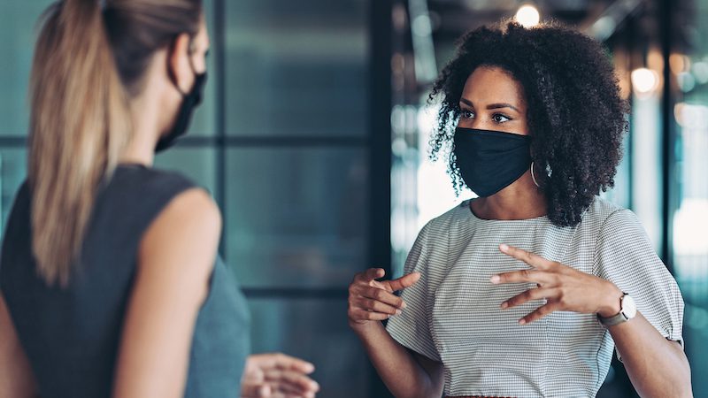 Black woman with mask talking to white woman with mask teacher observation