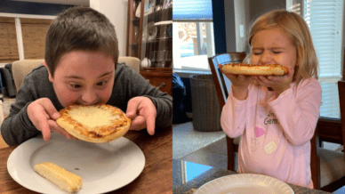 young boy and girl sitting at a table biting into pizza during pizza school funderaisers