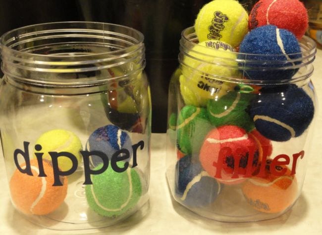 Two plastic jars labeled dipper and filler, with some colorful tennis balls in each