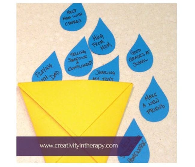 Small yellow origami paper bucket with blue paper raindrops with bucket filler activities written on them