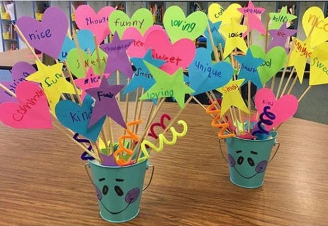 Miniature buckets with smiling faces filled with paper shapes on sticks with kind words written on each shape as an example of bucket filler activities