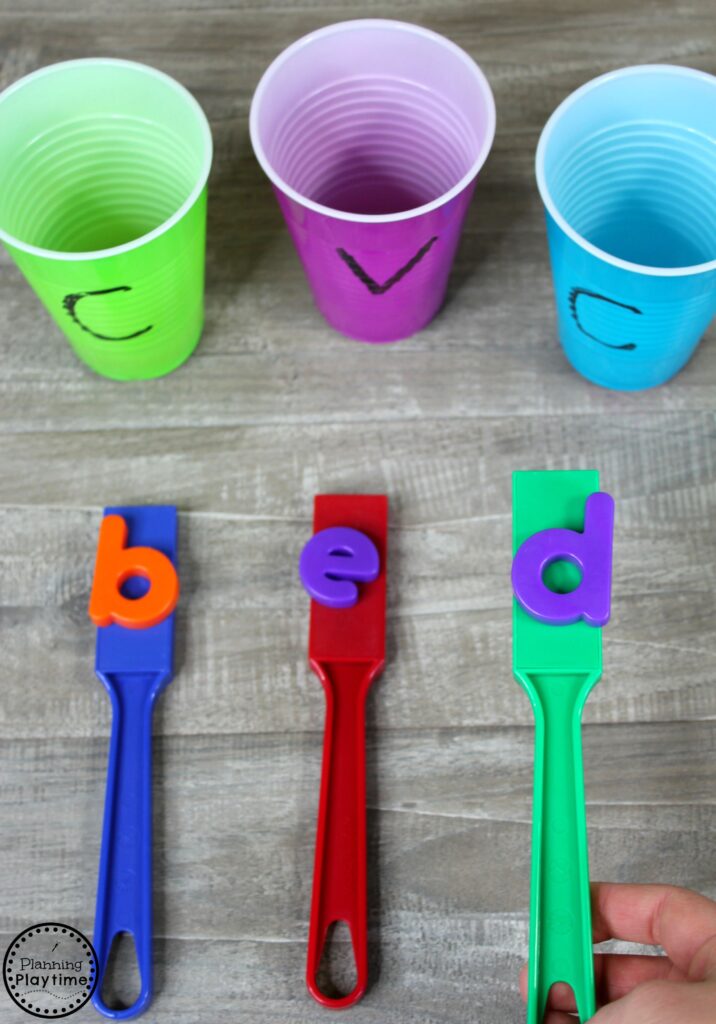 magnets with letters attached spelling the word "bed" with three cups in the background 