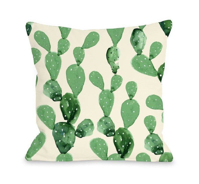 Beige throw pillow decorated with various green cacti